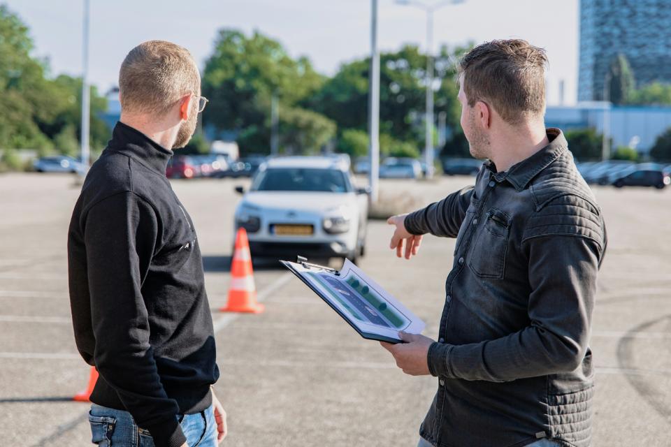 Two men discussing driving instructions outdoors