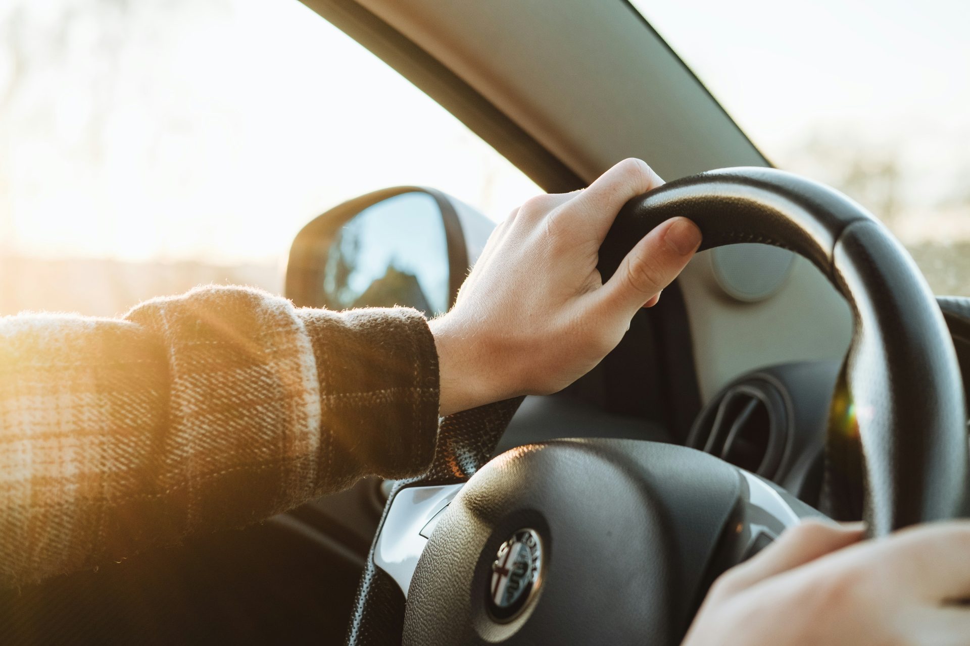 Driver's hand gripping Alfa Romeo steering wheel